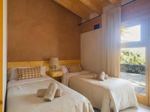 two beds in a room with a window at Casa rural, de estilo moderno, en gran canaria in Taidía
