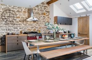 a kitchen with a table and a stone wall at Le Rooftop Loft premium 3 chambres avec terrasse & parking en centre-ville de Saint-Étienne in Saint-Étienne