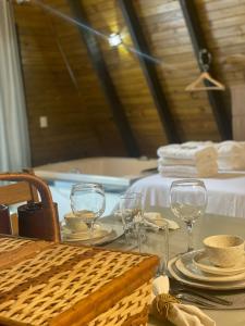 a table with glasses and plates on it with a tub at Chalé refúgio das águas in Ituporanga +55 photos