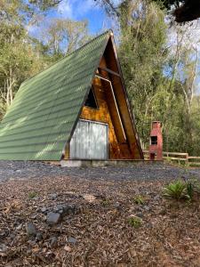 a house with a green roof on a forest at Chalé refúgio das águas in Ituporanga
