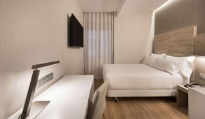 Una pequeña habitación de hotel con una cama y un escritorio. en NH Madrid Chamberí, en Madrid