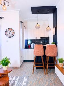 une cuisine avec des armoires blanches et des chaises orange dans une pièce dans l'établissement Five-Eight Residences, à Jinja