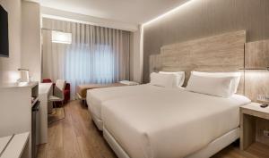 Una gran cama blanca en una habitación de hotel. en NH Madrid Chamberí, en Madrid