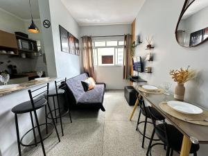 ein Wohnzimmer mit einer Bar, einem Tisch und Stühlen in der Unterkunft Boqueirão: 50m do mar e perto de tudo! in Praia Grande