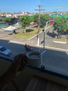 a person holding a cup of coffee on a window sill at Hotel Renascer pojuca in Pojuca