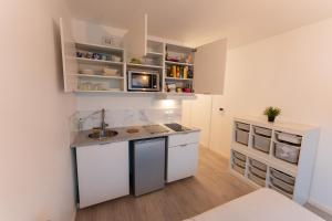 a small kitchen with white cabinets and a sink at Studio à Disneyland Paris in Coupvray