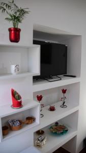 a room with white shelves with a tv and flowers at Paloma nel bosco in Sutri