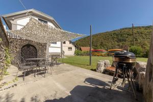 a grill in a backyard with a table and chairs at doLodge homestead in the Kolpa River canyon in Stari Trg ob Kolpi