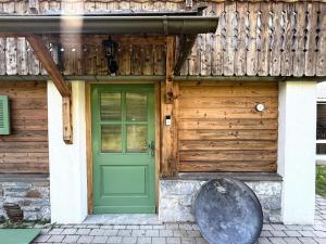 Una puerta verde en una casa de madera con una rueda de metal. en das Sopherl, en Sonnenalpe Nassfeld