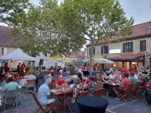 a group of people sitting at tables at an outdoor restaurant at Le Citrus in Excideuil