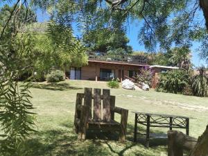 a wooden bench sitting in the grass in front of a house at Vinoteca cerro in Piriápolis