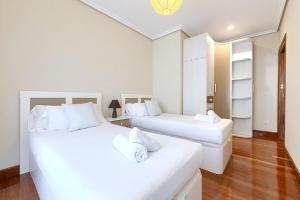 Habitación con 2 camas, paredes blancas y suelo de madera. en Acogedor apartamento en Gernika, en Guernica y Luno