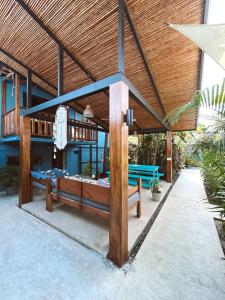 a patio with two benches under a wooden roof at Point Break Santa Teresa in Santa Teresa Beach