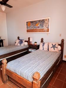 a bedroom with two beds and a painting on the wall at Residência hoteleira Aldeia da Praia Guarapari in Guarapari +34 photos