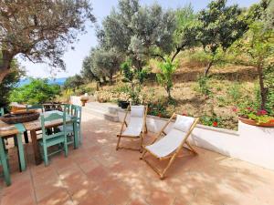 un patio con mesa, sillas y árboles en Nucidda - Country House with sea & mountain views, en Reitano