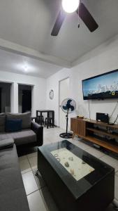 a living room with a couch and a flat screen tv at El Arrecife: Apartamento con alberca a 10 minutos de la playa in Acapulco