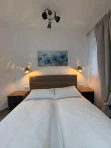 a bedroom with a large white bed with two lights at Family Apartments Zemlinsi 2 in Payerbach