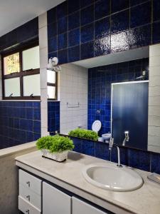 a bathroom with a sink and blue tiles at Residência hoteleira Aldeia da Praia Guarapari in Guarapari
