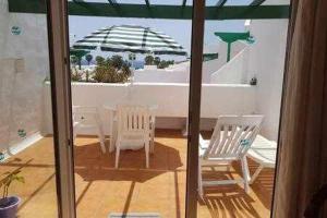 two chairs and a table and an umbrella on a balcony at Bonito apartamento reformado en Las Coronas in Costa Teguise