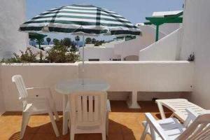 a table and chairs and an umbrella on a balcony at Bonito apartamento reformado en Las Coronas in Costa Teguise