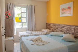Dos camas en una habitación con paredes amarillas y una ventana. en Ponta Negra_Apto Completo, en Natal 62 fotos más