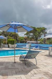 un banco con sombrilla junto a la piscina en Ponta Negra_Apto Completo, en Natal