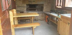 a kitchen with wooden benches and a stone fireplace at A Casa da Zalaroia, para amantes de la naturaleza in San Mamed