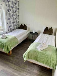 a bedroom with two beds with green blankets at KB Storhaugen House - Sørvågen in Moskenes