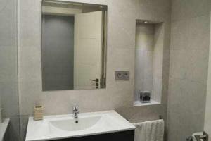 Un baño blanco con lavabo y espejo. en Apartamenticos Boggiero III, en Zaragoza