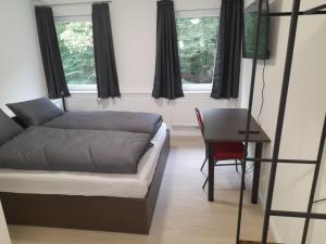 Un dormitorio con una cama y una mesa y ventanas. en Boardinghaus Waldesruh, en Lohne