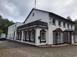 a white building with a black and red trim at Boardinghaus Waldesruh in Lohne