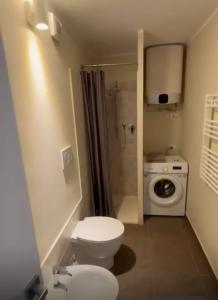 a bathroom with a toilet and a washing machine at Casa in Pineta in Follonica +5 photos