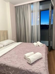 a bedroom with a bed with towels on it at Olive Dream Apartment with Balcony View in Tbilisi City