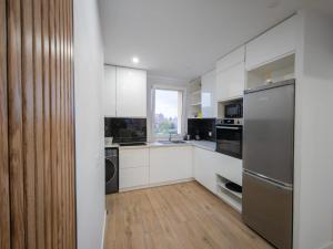 eine Küche mit weißen Schränken und einem Edelstahlkühlschrank in der Unterkunft Apartamento Santa Bárbara in A Coruña