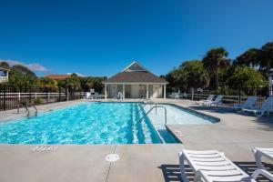 a swimming pool with chairs and a house at Retreat 5B - Edisto Blessing in Edisto Island
