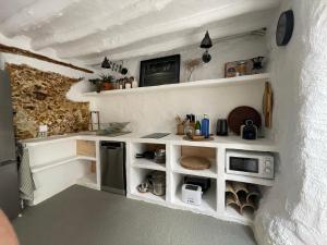 a small kitchen with white shelves and a microwave at Casa Tohca Setenil in Setenil