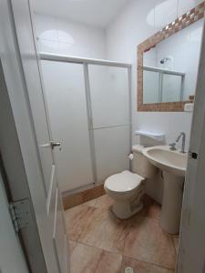a white bathroom with a toilet and a sink at Apartamento con vista a la playa frente al mar in El Recreo