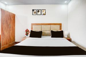 1 dormitorio con 1 cama blanca grande con almohadas negras en Hotel O DIAMOND INN, en Nueva Delhi
