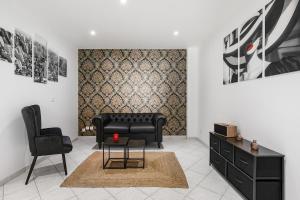 a living room with a black couch and a chair at Love Room Le Dungeon - Pézenas in Pézenas