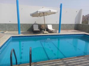 a swimming pool with two chairs and an umbrella at ashria pool gest house in Jazīrat Salūjah +2 photos