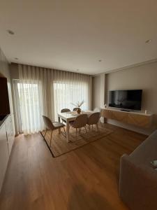 Una sala de estar con una mesa y sillas y un televisor. en Apartamento do Raio, en Braga