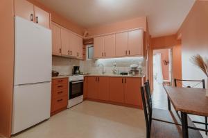 a kitchen with white appliances and a wooden table at Cozy Peach Nest in Tolo