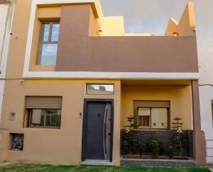 une maison avec une porte et des fenêtres noires dans l'établissement Oasis royale, à Dakhla