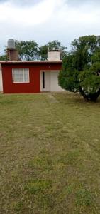 una casa rossa e bianca con un albero in un campo di San blas departamento a San Blas