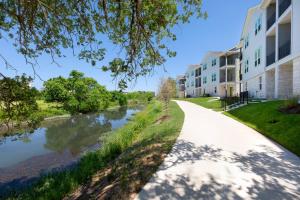 a walkway next to a river with apartment buildings at Cozy Stay in Heart of Leander in Leander +9 photos