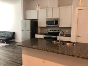 a kitchen with white cabinets and a sink and refrigerator at Cozy Stay in Heart of Leander in Leander