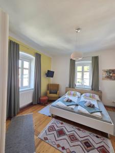 ein Schlafzimmer mit einem Bett und einer Couch und Fenstern in der Unterkunft Appartements Maximilian in Göstling an der Ybbs