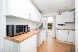 South Ruislip StationにあるFamily Friendly 3BR Haven in Northolt with Parkingのキッチン(白いキャビネット、電子レンジ付きのカウンター付) +10枚の写真