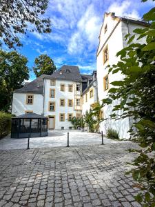 a large white building with a cobblestone courtyard at Schlosshotel Eyba in Saalfeld