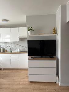 a kitchen with white cabinets and a flat screen tv at Apartament Stare Miasto Malbork in Malbork +3 photos